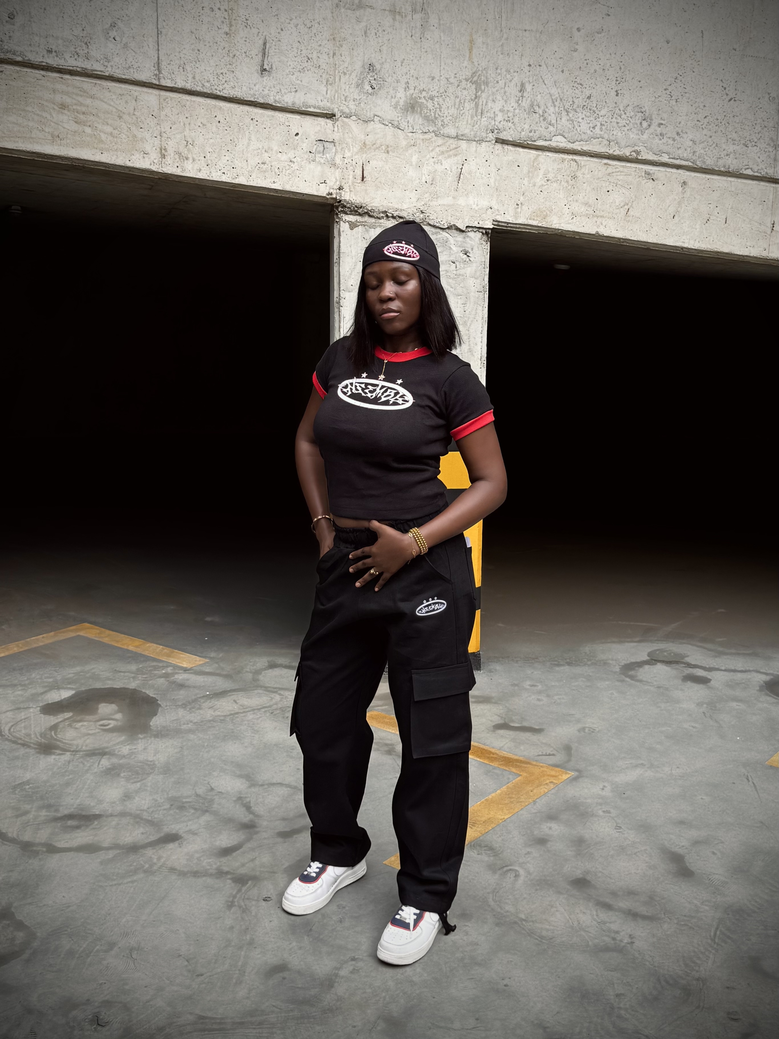 ENSEMBLE model in black and red streetwear inside a Lagos parking structure
